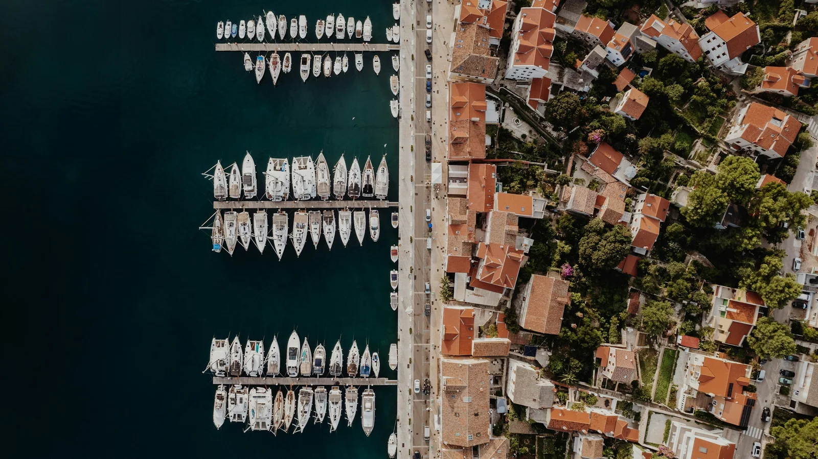 Aerial view of sailboats in the harbor beside red-roofed houses in Mali Lošinj